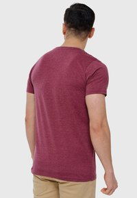 T-shirt corti maniche color mogano realizzato in tessuto morbido, con colletto rotondo e vestibilità regolare. Design semplice senza fantasie o dettagli.