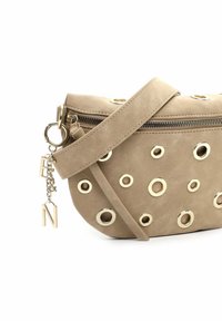 Beige suède handtas met gouden ringen als accenten, een ritssluiting en een decoratieve gouden letterhanger bevestigd aan de riem.