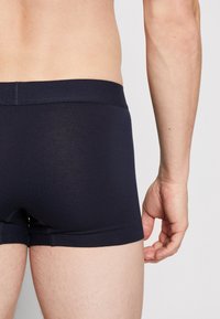 Marineblaue Baumwollboxershorts mit einem weichen Bund, passgenauer Form und glatter Textur, die einen einfachen, schlichten Stil zeigen.