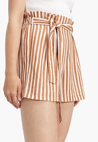 Pantalones cortos a rayas con cinturón atado, con rayas alternas en naranja y blanco, ajuste relajado y un bolsillo con solapa en el lateral.