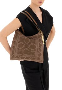 Borsa a tracolla in pelle marrone con motivi floreali in rilievo, dotata di tracolla color cuoio e accessori in tono dorato. Forma rettangolare sofisticata.