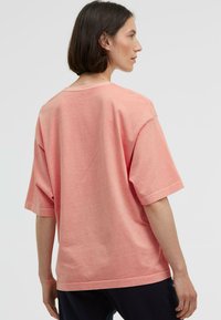 Helles rosa Oversize-T-Shirt mit kurzen Ärmeln, rundem Hals und glatter Textur. Einfaches Design, ohne Muster oder Verzierungen.