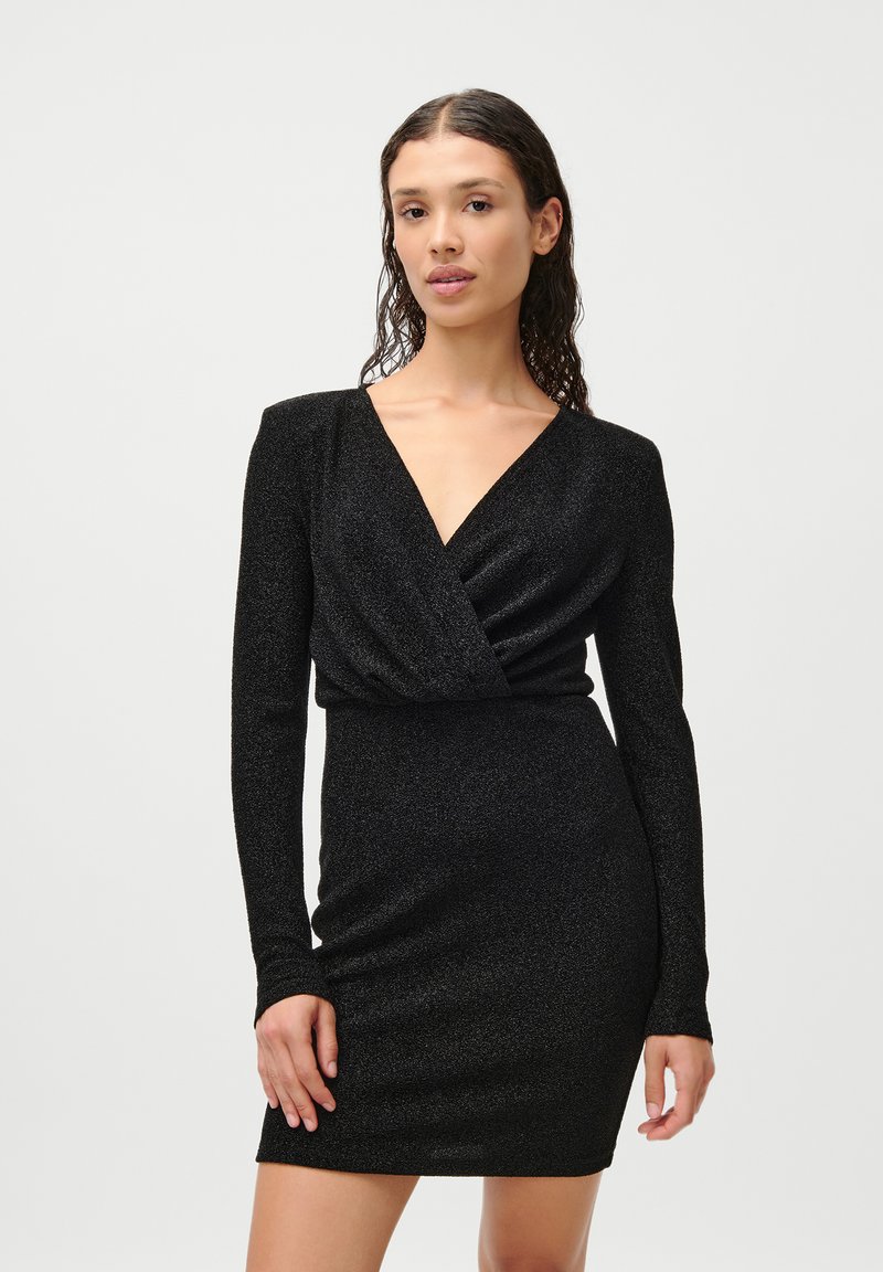 Μαύρο φόρεμα με μακριά μανίκια, V-λαιμόκοψη, σχεδίαση τύπου περιτυλίγματος και εφαρμοστό σιλουέτα. Η ελαφρώς λαμπερή ύφασμα προσθέτει υφή και οπτικό ενδιαφέρον.