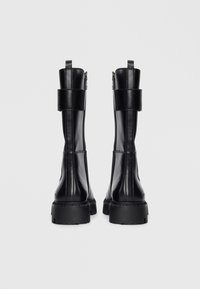 Black leather ankle boots with a smooth texture, padded ankle strap, and chunky rubber sole. Features side zippers for easy access.