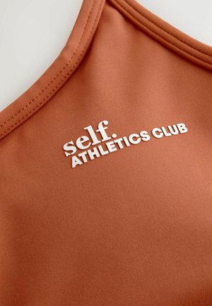 Pronksine sportlik tank-top sujuva tekstuuriga, millel on valge kiri "self. ATHLETICS CLUB" ja ümar kaelus.