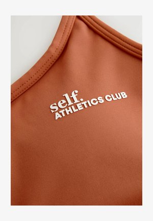 Bronza sporta T-kreklu ar gludu tekstūru, ar baltu uzrakstu "self. ATHLETICS CLUB" un noapaļotu kakla izgriezumu.