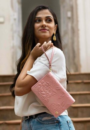 Roze reliëf portemonnee met bloemen- en vlinderpatronen, voorzien van een polsband en gouden hardware accenten. Gladde leertextuur.