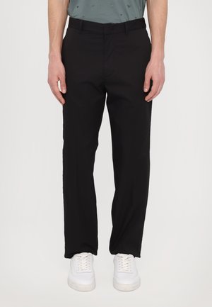 Black trousers made of smooth fabric with a straight cut, featuring side pockets and a flat front. Worn with white sneakers.