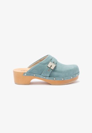 Jasnoniebieskie zamszowe chodaki z drewnianą podeszwą, metalowymi ćwiekami wzdłuż krawędzi oraz regulowanym paskiem z boczną klamrą.