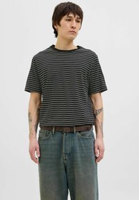 Stripet sort-hvid kortærmet T-shirt med rund hals, parret med løstsiddende blå denimjeans og et brunt bælte. Minimalistisk design.