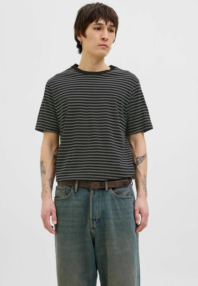 Stripet sort-hvid kortærmet T-shirt med rund hals, parret med løstsiddende blå denimjeans og et brunt bælte. Minimalistisk design.
