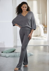 Grijze gebreide lounge set met een losse V-hals top en flare broeken met een getextureerd ribbelontwerp en voorzakken.