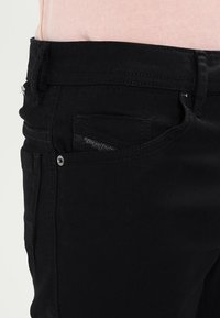 Svarta denimjeans med en figurnära passform, som har en liten framficka och en diskret Diesel-logotagg. Slät textur och minimal hårdvarudetalj.