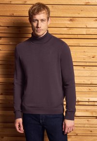 Pullover-Pullover in dunklen lila, mit einem hohen Kragen und langen Ärmeln, aus weichem Material mit einer taillierten Passform gefertigt.