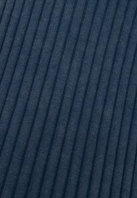 Marineblauwe ribstof met verticale strepen, die een gestructureerd oppervlak en gelijkmatig verdeelde groeven laat zien. Het materiaal lijkt zacht en brei-achtig.