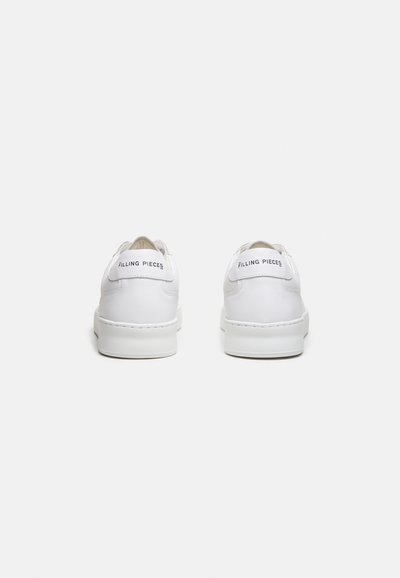 Paar weiße Low-Top-Sneaker mit "FILLING PIECES" Text auf der Fersenschlaufe, von hinten auf weißem Hintergrund gezeigt.