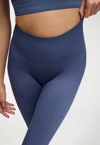 Legginsy o wysokim stanie w jednolitym ciemnoniebieskim kolorze, z prążkowaną teksturą i gładkim, elastycznym paskiem w talii dla dodatkowego komfortu i dopasowania.