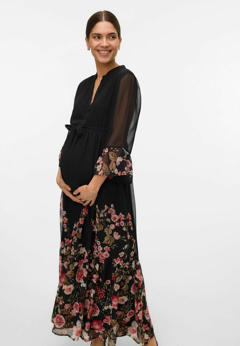 Maxi dress in black with floral print. Features sheer sleeves, a tie at the waist, and a flowing skirt, highlighting textures and patterns.