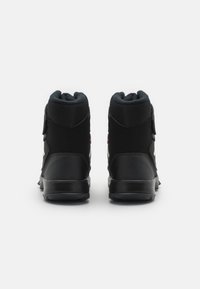Zapatillas altas negras con una base de cuero suave, paneles de malla y acentos reflectantes. Cuentan con correas de Velcro para un ajuste seguro.