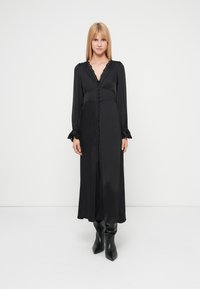 Black long-sleeve dress with a deep V-neck, featuring a button-down front, gathered waist, and ruffled cuffs. Smooth texture and flowing design.