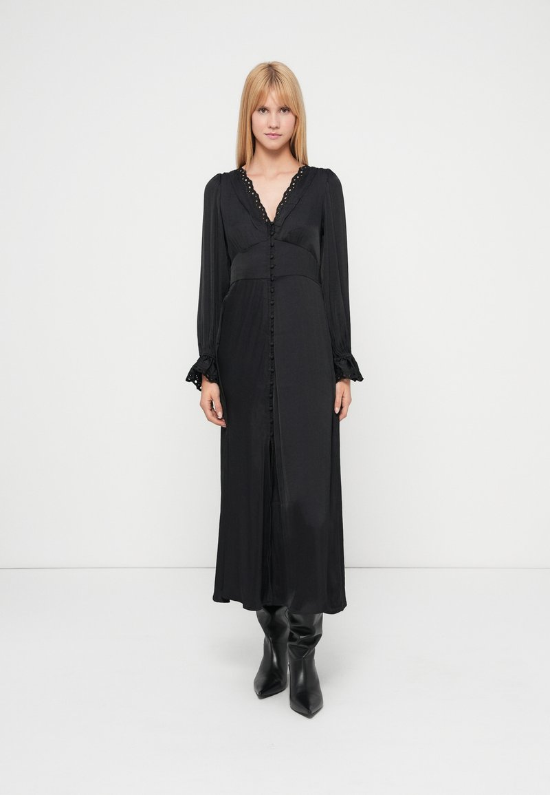 Black long-sleeve dress with a deep V-neck, featuring a button-down front, gathered waist, and ruffled cuffs. Smooth texture and flowing design.