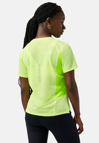 Camiseta deportiva Brooks de color amarillo neón que cuenta con un tejido transpirable y texturizado, mangas cortas y un logotipo reflectante en la parte posterior.