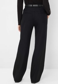 Pantalon noir à larges jambes en tissu lisse, avec deux poches arrière et une ceinture noire texturée soulignant la taille.