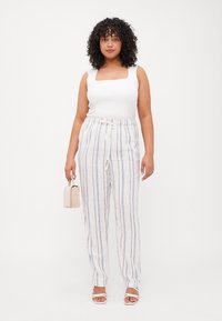 Top sin mangas de cuello cuadrado blanco combinado con pantalones ligeros a rayas en crema, azul y gris, con cintura con cordón y un ajuste relajado.