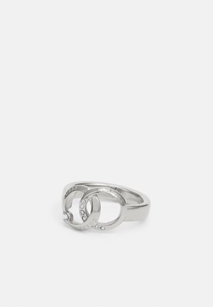 Sølvring med to sammenlåste cirkler, graveret med "GUESS" og "FOREVER,", hver prydet med små klare krystaller.