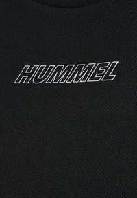 Svart texturerad tyg med rund halsringning där ordet "HUMMEL" i fet vit text pryder framsidan.
