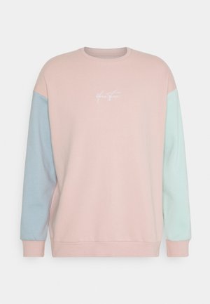 Bluza w kolorze pastelowego różu z jasnoniebieskimi i miętowozielonymi rękawami, z okrągłym dekoltem i białym, kursywnym logo na środku klatki piersiowej.