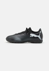 Zapatillas deportivas negras con una parte superior texturizada, que presentan un sutil patrón diagonal. Muestran un logo blanco en contraste en el talón.