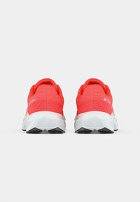 Pair of bright red athletic shoes with white soles viewed from the back, showing textured heel design and "NB Propel" branding.