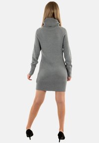 Abito maglione grigio a collo alto, con maniche lunghe e design aderente, che termina a metà coscia. Tessuto morbido con dettagli a coste.