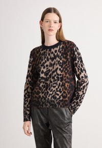 Pull en tricot à imprimé léopard avec des couleurs brunes, beiges et noires. Col rond, manches longues et détail de bord-côte.