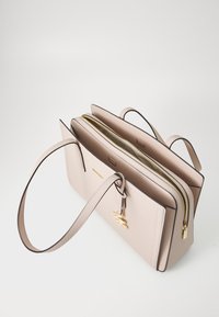 Beige leren handtas met twee ritscompartimenten, platte bodem en lange schouderbanden. Beschikt over gouden hardware en een decoratieve charme.