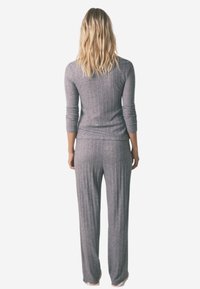 Grå ribbede loungewear sæt inkluderer en langærmet top og bukser, der har en afslappet pasform og blød tekstur. Minimalistisk design uden mønstre.