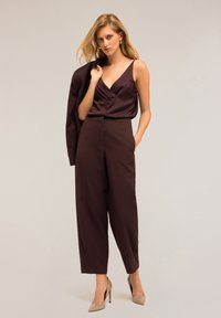 Bordeaux satijnen top met gedrapeerde halslijn, gecombineerd met hoge taille wijde broek. Beige hakken maken de outfit compleet.