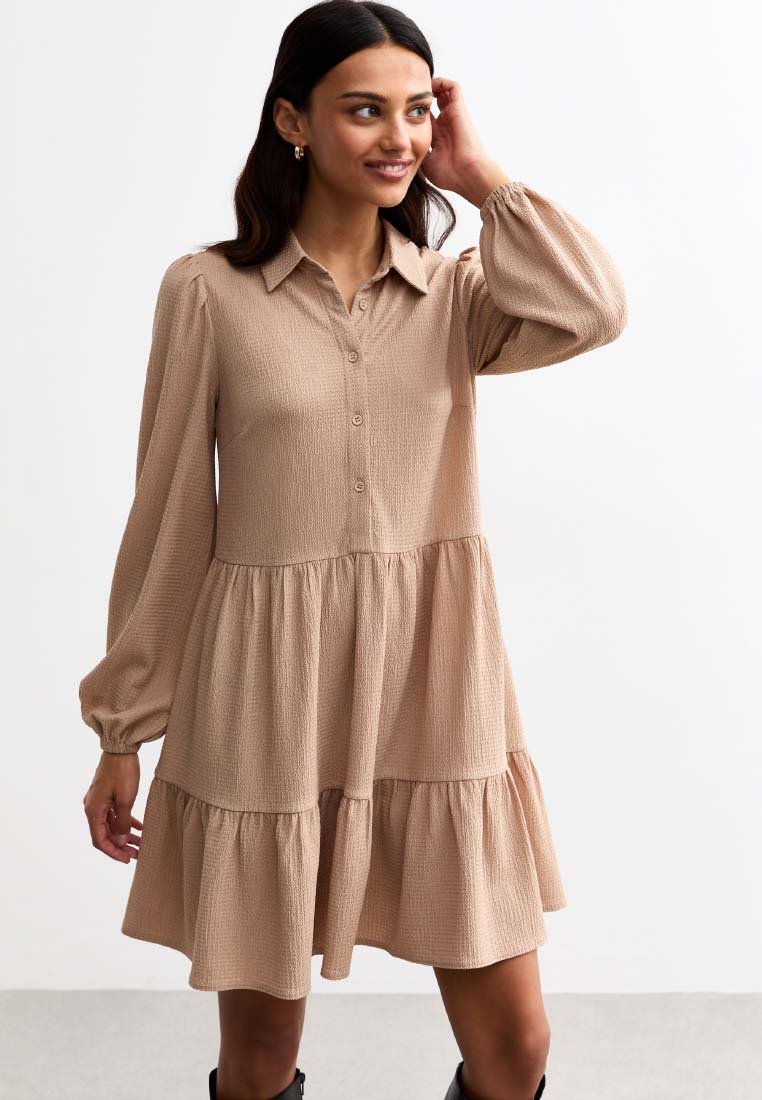 Light brown dress with a button-up front, collared neckline, and long sleeves. Features a tiered skirt with a textured fabric.