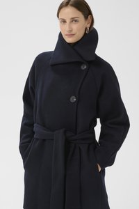 Tengerészkék gyapjú kabát magas gallérral, gombos záródással és derékpánttal. Zsebekkel és puha, texturált anyagból.