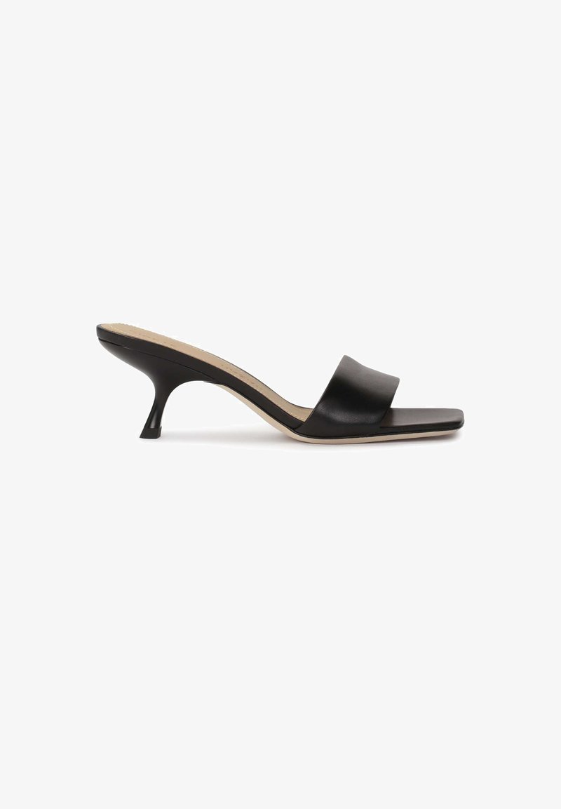 Mules à talons en cuir noir avec une large sangle et un bout pointu. Le talon est fin et légèrement courbé, avec une semelle intérieure beige.