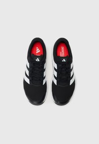 Black athletic shoes featuring a mesh upper, three white stripes, and a red insole labeled "adidas TRAINING." Smooth rubber outsole.