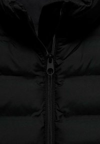 Svart vadderad jacka med hög krage, med en central dragkedja och quiltad struktur. Materialet ser glänsande och slätt ut.