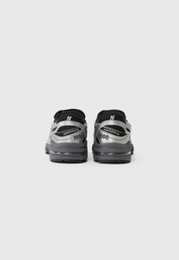 Rear view of gray and black New Balance 1000 sneakers, featuring a mesh upper, cushioned sole, and reflective accents.