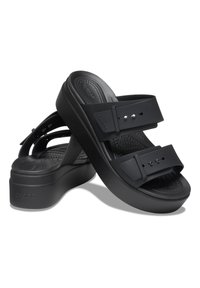 Black platform sandals with two adjustable straps, featuring a textured footbed and smooth sole. Minimalist design with rounded edges.