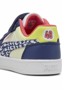 Fehér talpú sneaker, tengerészkék és sárga szintetikus felsőrésszel, híg-hígdami mintázattal, rózsaszín díszítésekkel és "48" felirattal a saroknál.