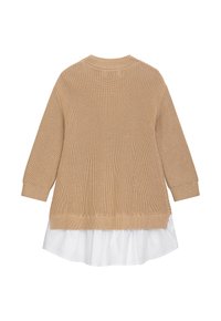 Beige gestrickter Pullover mit langen Ärmeln und geripptem Saum, über einem weißen Hemd mit abgerundetem Saum und sichtbarer Textur getragen.