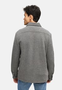 Grå stribet skjorte med en blød tekstur, knappede manchetter og en klassisk krave. Designet har lodret ribbing og en afslappet pasform.