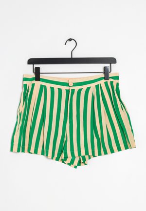 Shorts à rayures verticales vertes et beige avec fermeture par bouton, plis et poches latérales suspendus sur un cintre noir sur fond blanc.