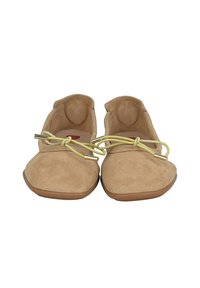 Ballerines en suede beige avec un bout arrondi, dotées d'un détail en lacet jaune et d'accents métalliques. La semelle est brune et légèrement surélevée.
